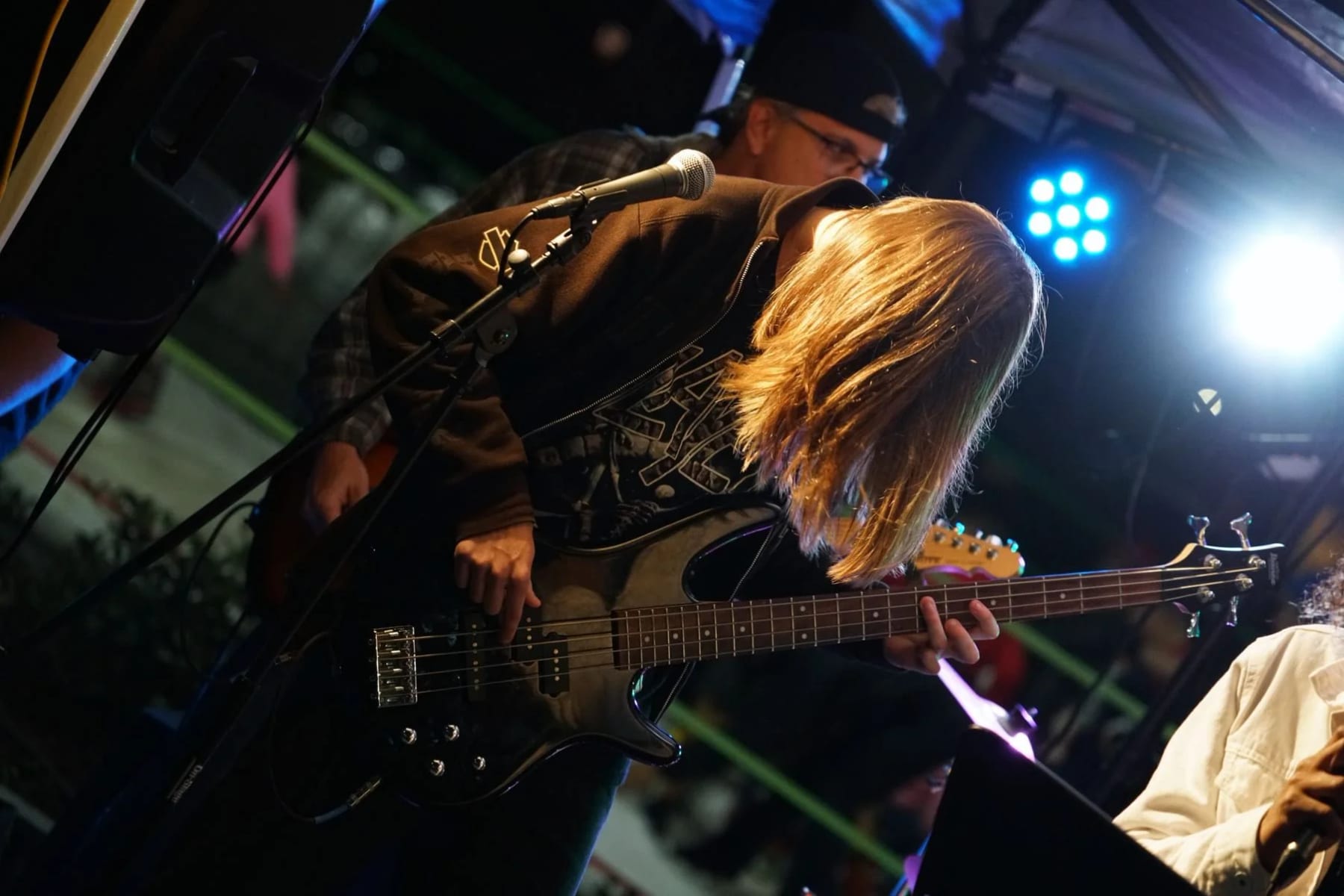 A Let There Be Rock School student playing bass on stage with an instructor beside them