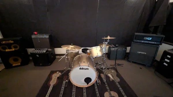 A Let There Be Rock School rehearsal room with a ddrum kit, guitar and bass amplifiers and a PA