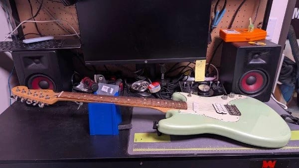 An electric guitar body on the repair bench at Let There Be Rock School, next to studio monitors and tools