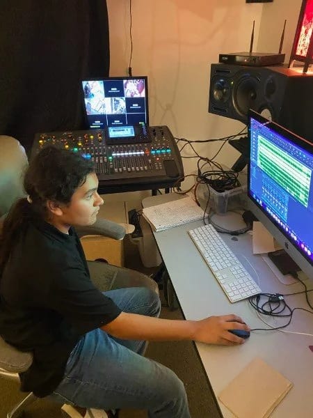 A Let There Be Rock School student at the recording console with a mixing surface and a DAW session open on screen