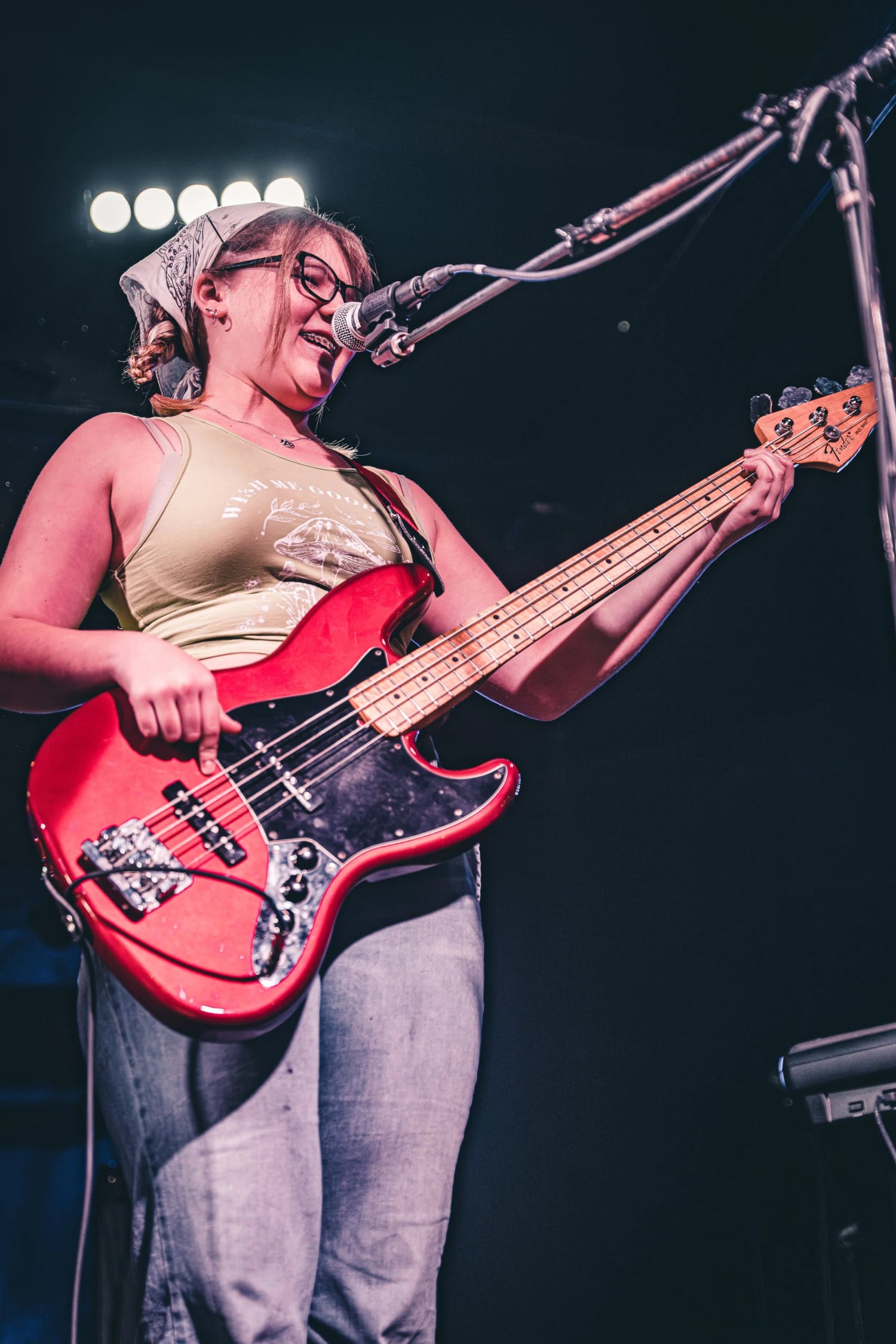 A student singing into the mic while playing a red Precision bass