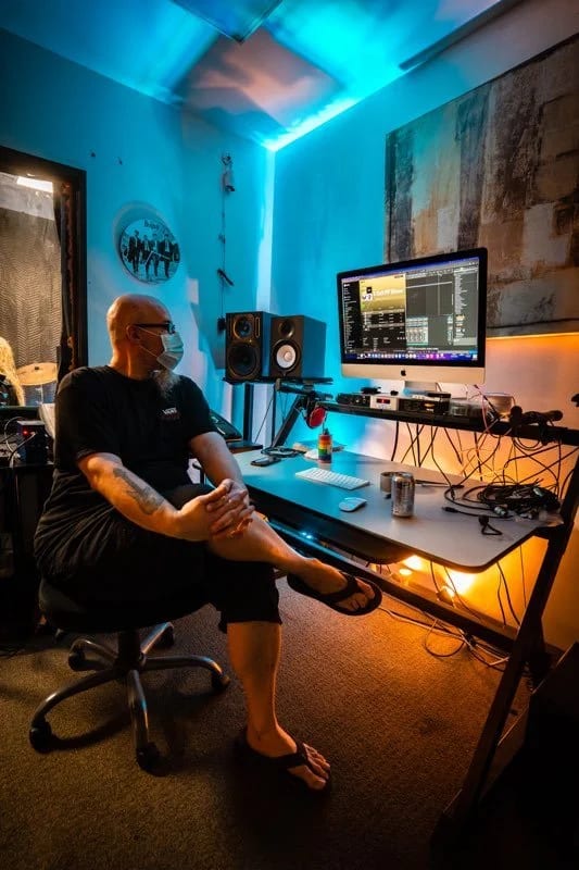 The Let There Be Rock School recording studio desk, with monitors, interface and a control surface under blue and amber light