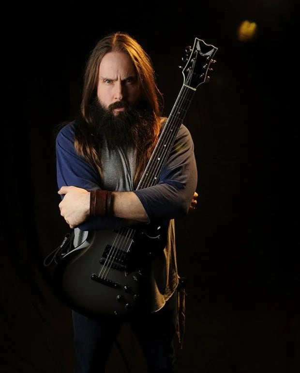 Eddie Veliz standing with an electric guitar against a black backdrop